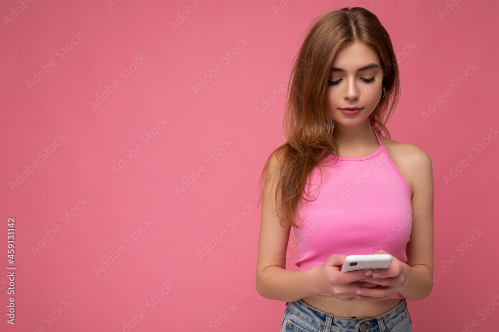 Beautiful young woman wearing casual clothes standing isolated over background surfing on the internet via phone looking at mobile screen Beautiful young woman wearing casual clothes standing isolated over background surfing on the internet via phone looking at mobile screen