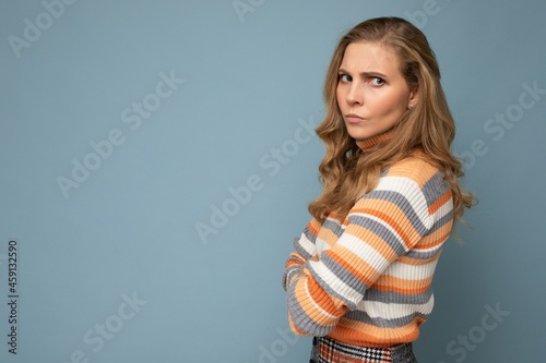 Photo portrait of young pretty beautiful angry dissatisfied blonde woman with sincere emotions wearing casual striped sweater isolated over blue background with copy space
