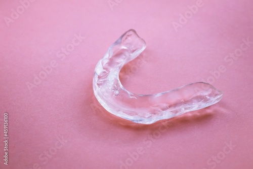 Dental splint on pink background for supporting structures and teeth from damage by grinding or clenching. photo