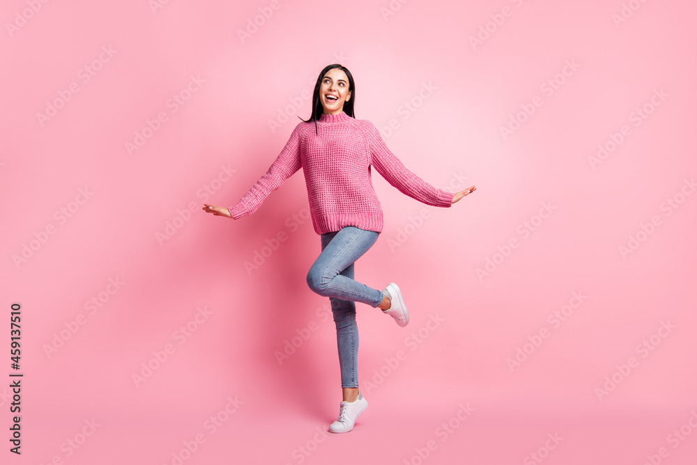 Full length photo portrait of cute dreamy girl standing on one leg isolated on pastel pink colored background
