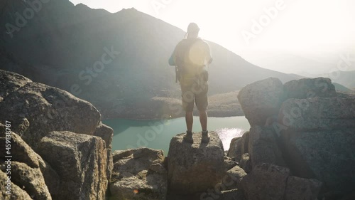 Hiker tourist with backpack taking photograph at smartphone at mountain lake photo