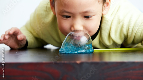 Fotografia Asian little girl playing with colloidal bubbles indoors