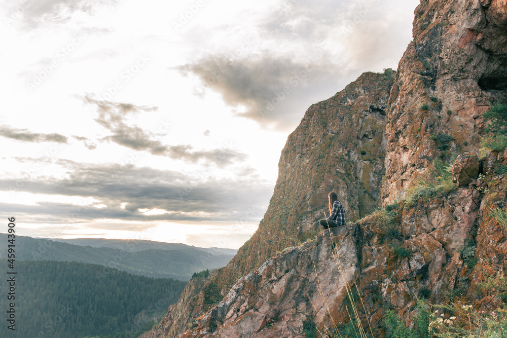 View of a meditating girl on a rock against the backdrop of a river valley. The concept of harmony with nature. Outdoor meditation. View of a meditating girl on a rock against the backdrop of a river valley. The concept of harmony with nature. Outdoor meditation.
