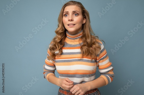 Photo portrait of young attractive beautiful sad upset touchy blonde woman with sincere emotions wearing striped pullover isolated on blue background with copy space and worries about