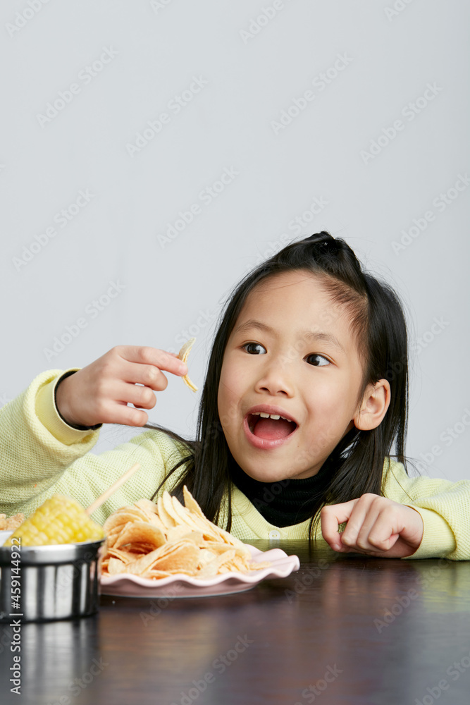 Asian little girl eating and playing indoors by herself Asian little girl eating and playing indoors by herself