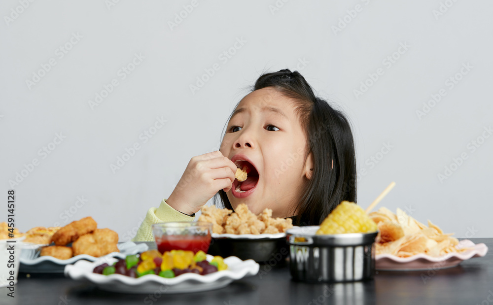 Asian little girl eating and playing indoors by herself Asian little girl eating and playing indoors by herself