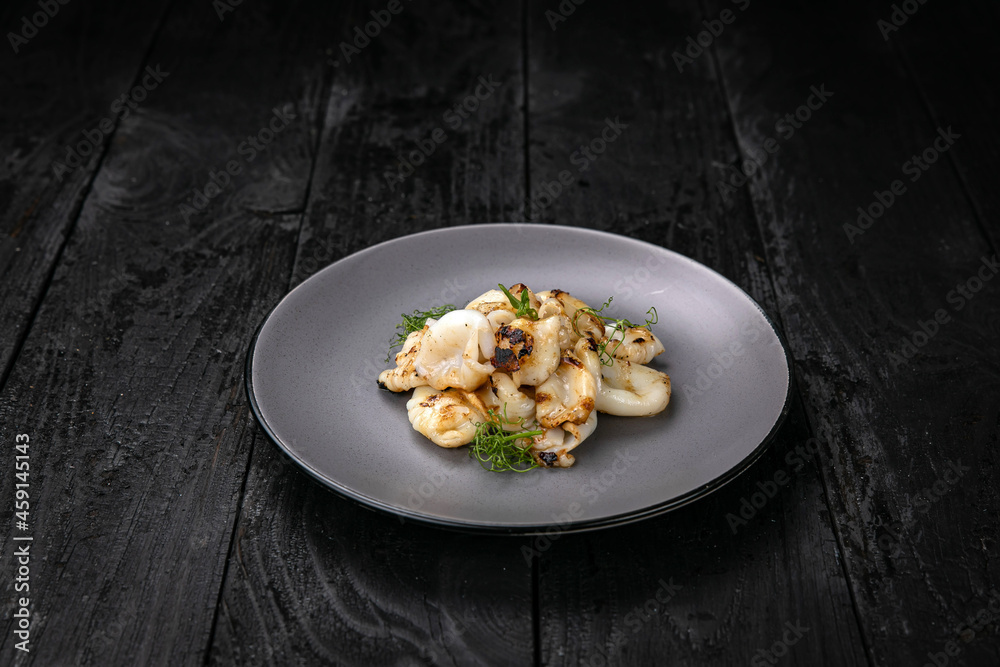 Seafood in a gray plate on a dark wooden table
