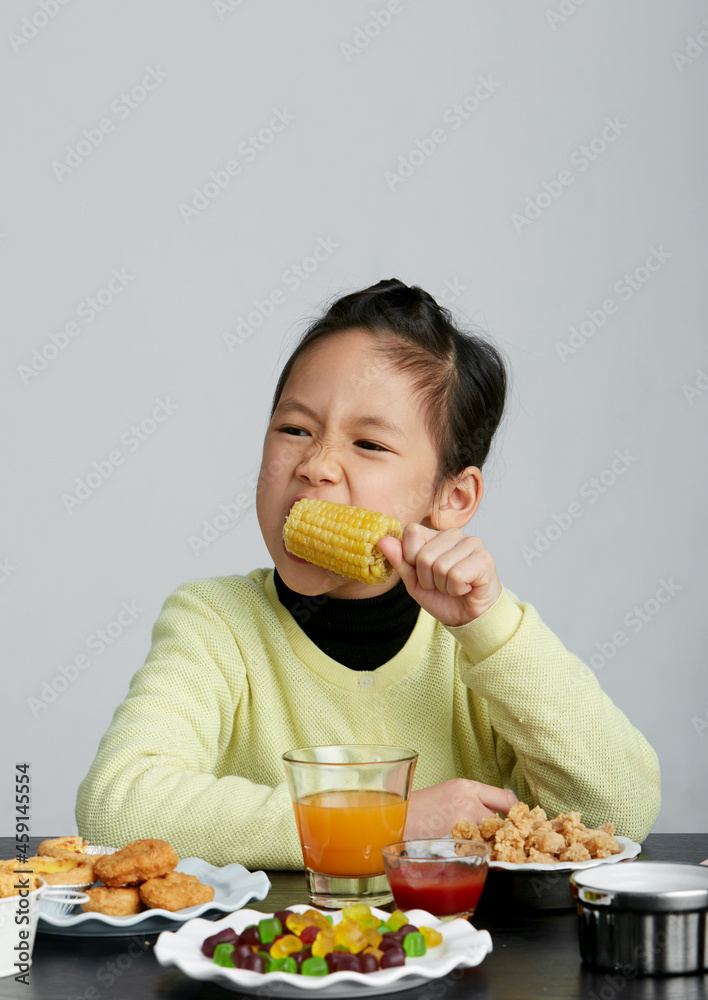 Asian little girl eating and playing indoors by herself Asian little girl eating and playing indoors by herself