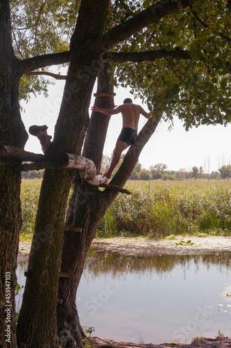 A young man stands on a tree above the river. Quality image for your project