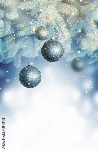 Christmas balls on a blue Christmas tree branch over blurred shiny background. Space for text