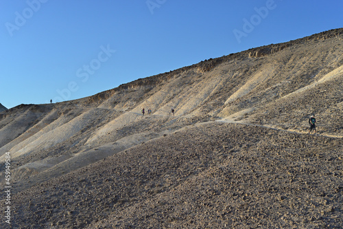 Group of tourists hiking. Group of travelers on a trail in an Israeli desert mountains, Ramon crater valley. backpackers tourists group walking hiking rocks desert path trail. 