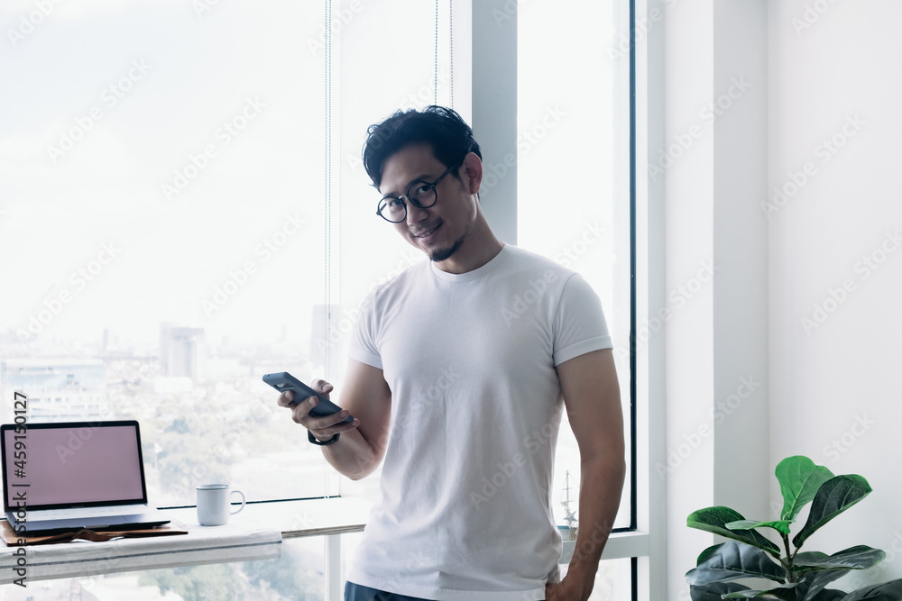 Happy Asian man using smartphone with balcony view. Concept work from home. Happy Asian man using smartphone with balcony view. Concept work from home.
