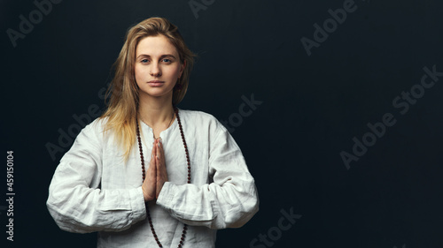Canvas Print Portrait of a yogi woman doing namaste mudra on a black background