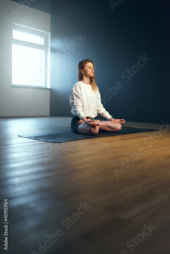 Young woman sitting in pranayama with jnana mudra. Yoga practice in the studio. photo