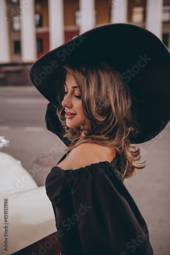 Photography Portrait of a beautiful girl in a black dress and black hat with wide brim