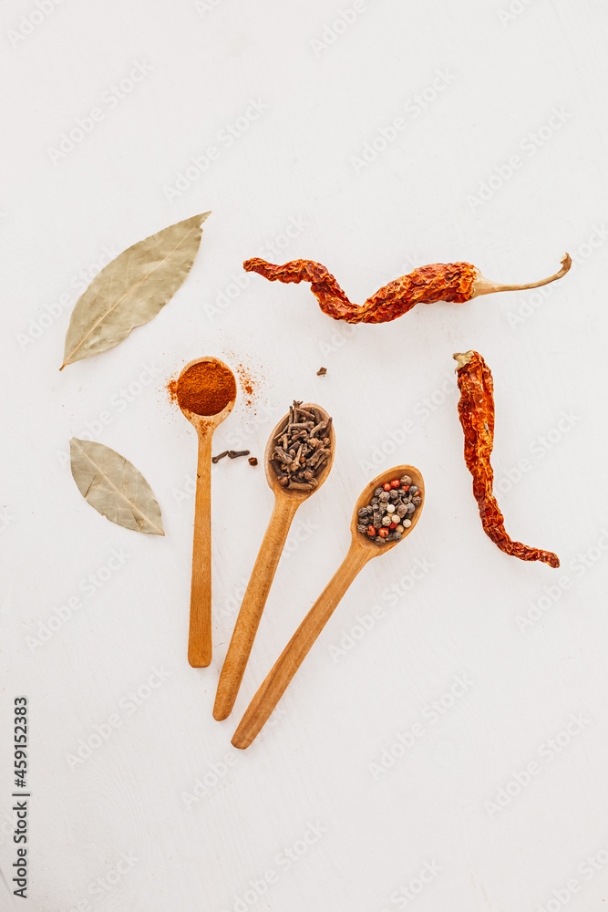 Spices in a wooden spoon. Herbs, curry, saffron, turmeric, cinnamon, bay leaf, peppers for cooking on a white background