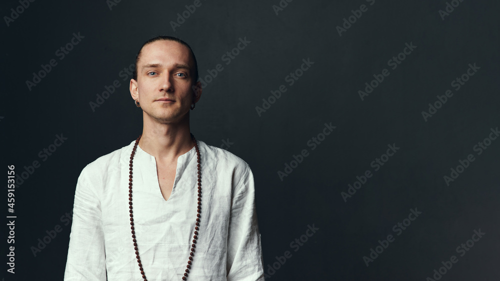 Fototapeta premium Yogi man in a white shirt on black background.