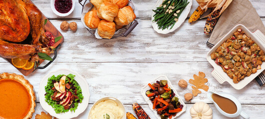 Traditional Thanksgiving turkey dinner frame. Overhead view on a rustic white wood banner background with copy space.