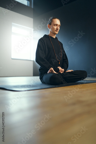 Young yogi man practicing meditation in lotus position.