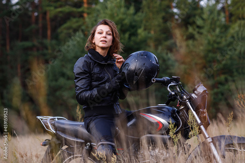 woman on a motorbike in nature. biker motorcycle ride through the woods