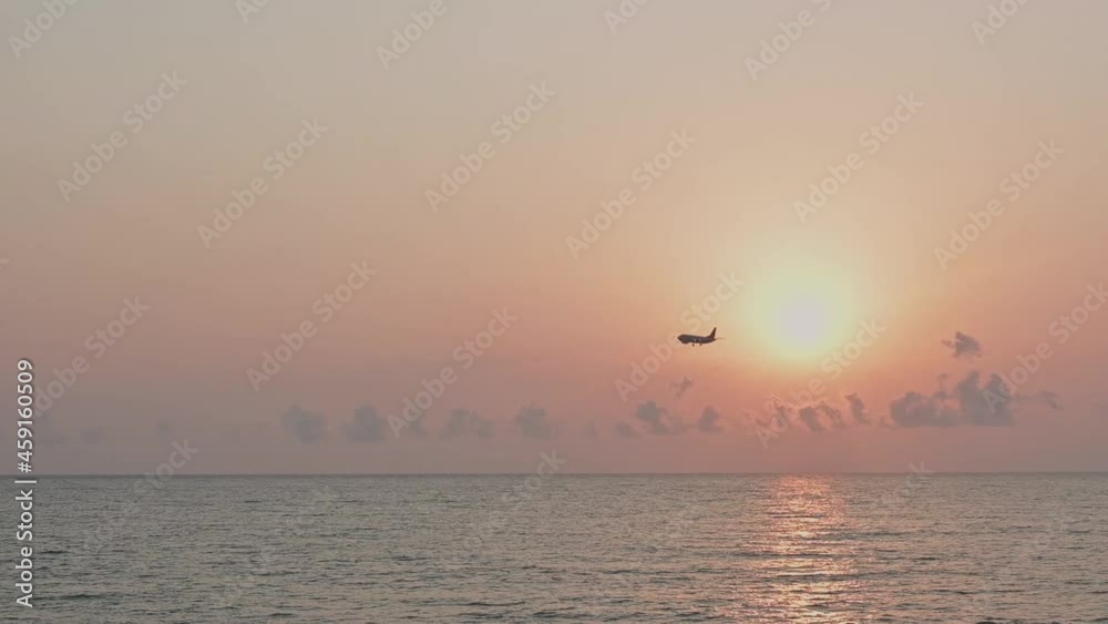 Airplane landing in the rays of the setting sun over the sea and glitter sun path, colorful sunset with an arriving plane, summer travel concept. Airplane landing in the rays of the setting sun over the sea and glitter sun path, colorful sunset with an arriving plane, summer travel concept.