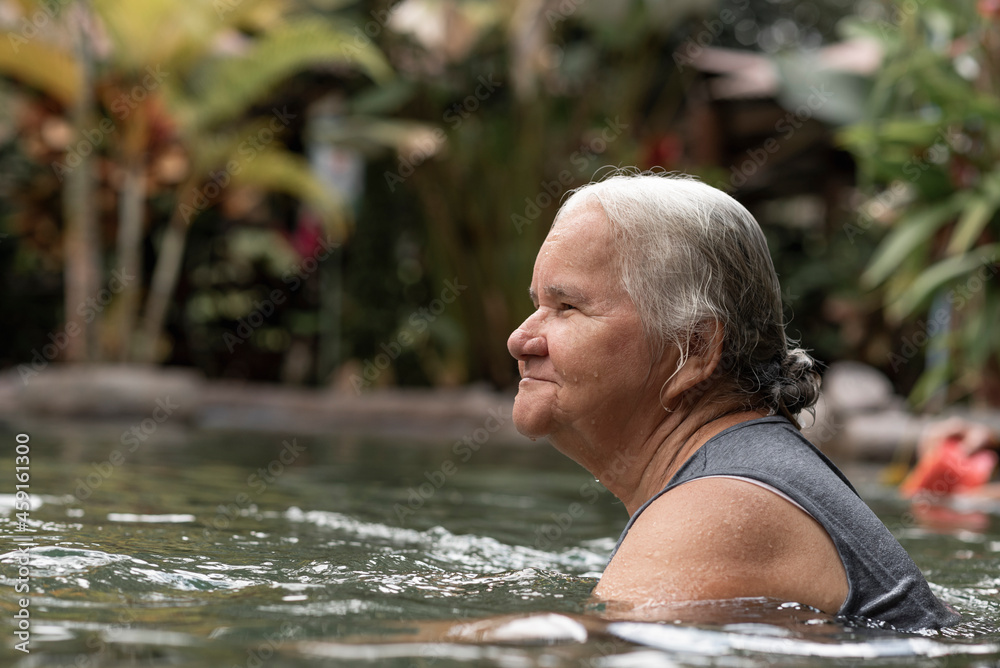 Fototapeta premium Mujer adulto mayor disfrutando de unas deliciosas aguas termales del Volcán Arenal de Costa Rica