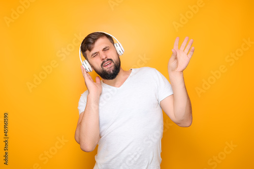 bearded man in musical headphones closed his eyes and listens to music. © Roman