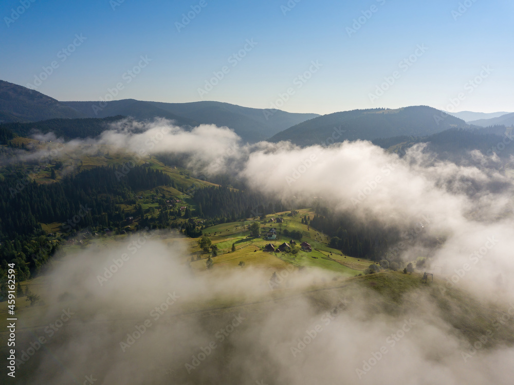 A thin morning fog covers the Ukrainian mountains. Green grass on the slopes of the mountains. A curly thin fog spreads over the mountains. Aerial drone view. A thin morning fog covers the Ukrainian mountains. Green grass on the slopes of the mountains. A curly thin fog spreads over the mountains. Aerial drone view.
