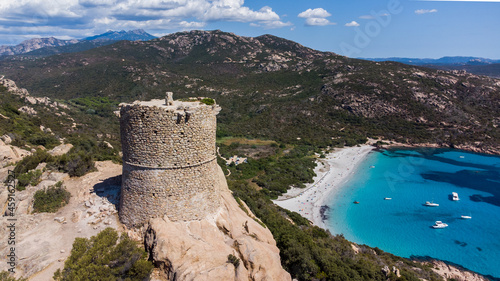 Aerial view of the ruins of the Genoese tower of Roccapina in the South of Corsica, France - Rounded tower overlooking the bay and beach of Roccapina with turquoise waters in the Mediterranean Sea