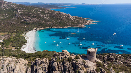 Aerial view of the ruins of the Genoese tower of Roccapina in the South of Corsica, France - Rounded tower overlooking the bay and beach of Roccapina with turquoise waters in the Mediterranean Sea photo