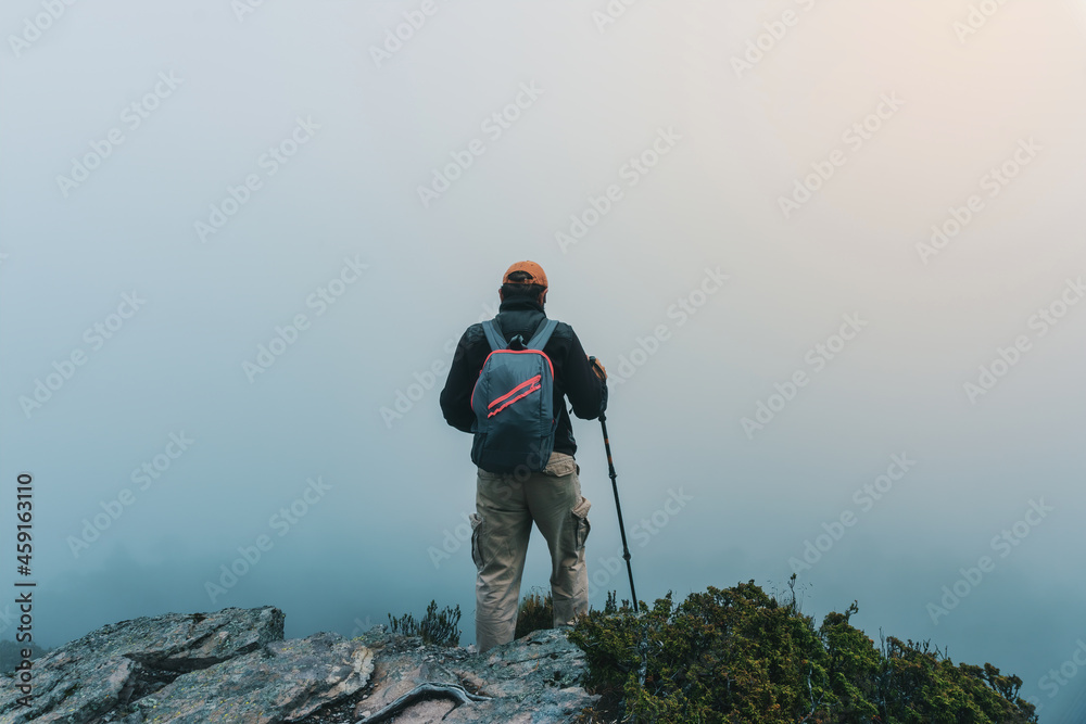 hiker standing on top of a cliff on a hill looking at the horizon . With copy space.