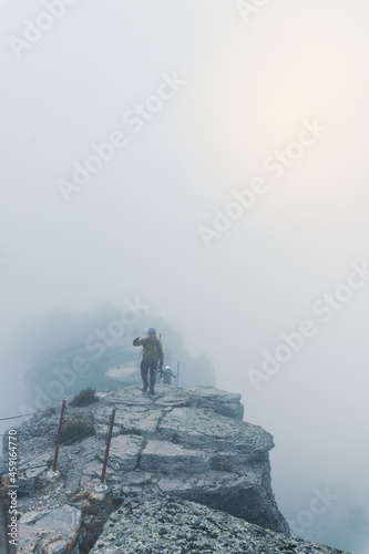 hiker standing on top of a cliff on a hill looking at the horizon . With copy space.