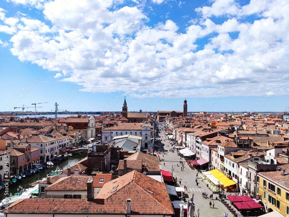 Panoramic view of the old town of Chioggia, Venice, from the bell tower, with red tiled roofs against blue cloudy sky 