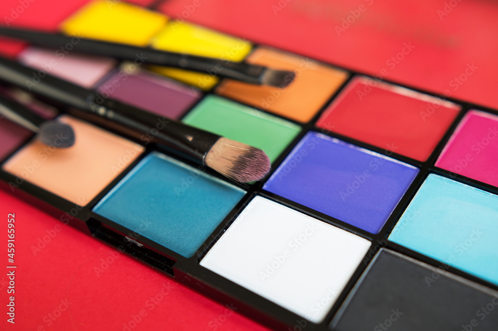 bright eyeshadows and makeup brushes on a red background bright eyeshadows and makeup brushes on a red background