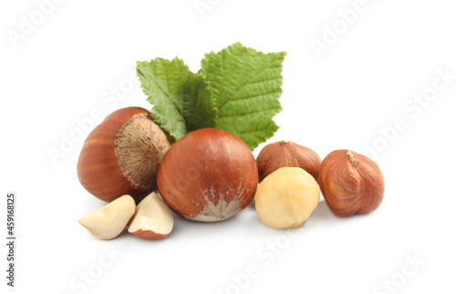 Tasty organic hazelnuts and leaves on white background