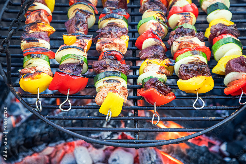Hot skewers on grill with vegetables. Skewers on fire.