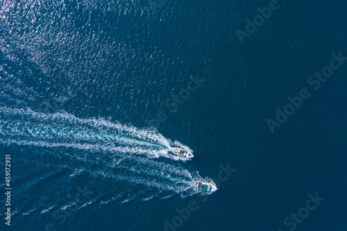 Two boats floating on the sea at high speed drone view.