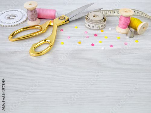 Scissors,thimble and spools of thread on the table.Sewing accessories.