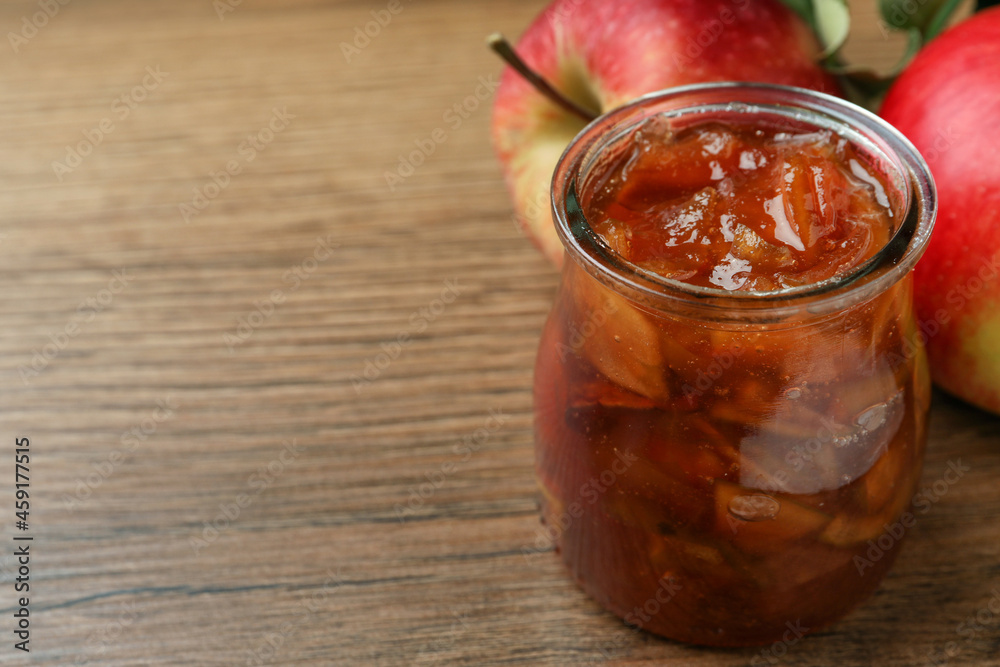 Tasty apple jam in glass jar and fresh fruits on wooden table, closeup. Space for text Tasty apple jam in glass jar and fresh fruits on wooden table, closeup. Space for text