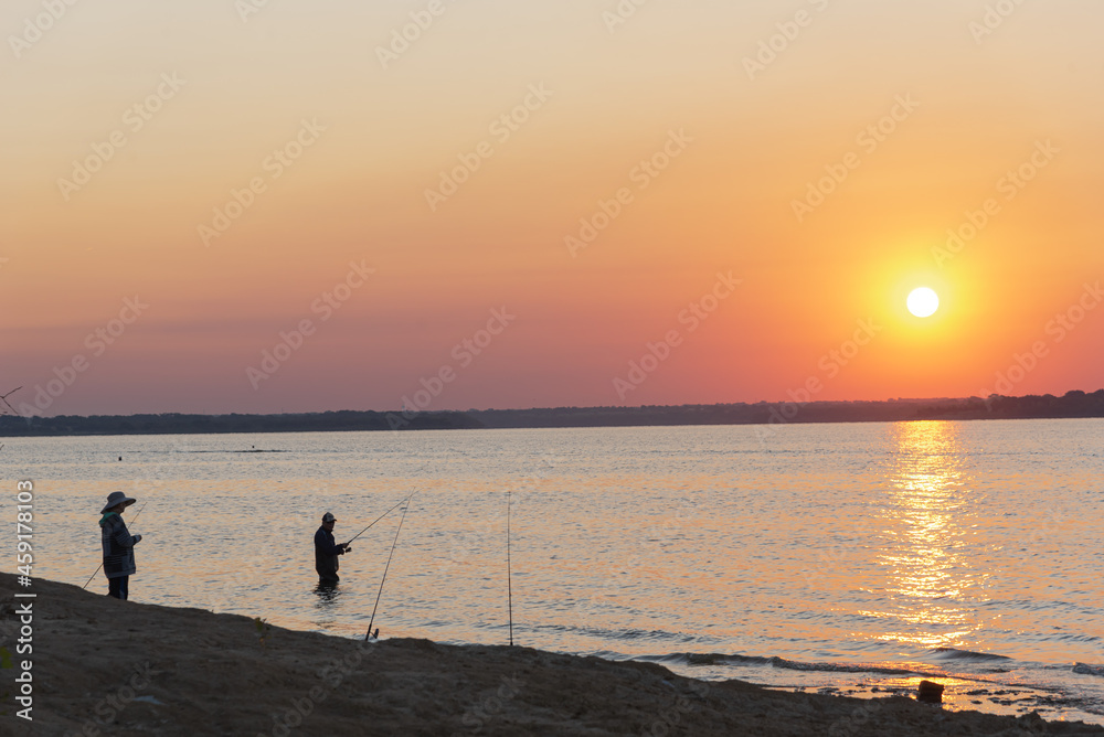 Two Asian men with boot and hat fishing at sunrise on Lavon Lake near Dallas, Texas, USA
