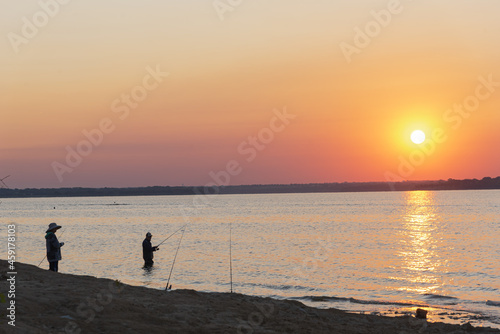 Two Asian men with boot and hat fishing at sunrise on Lavon Lake near Dallas  Texas  USA