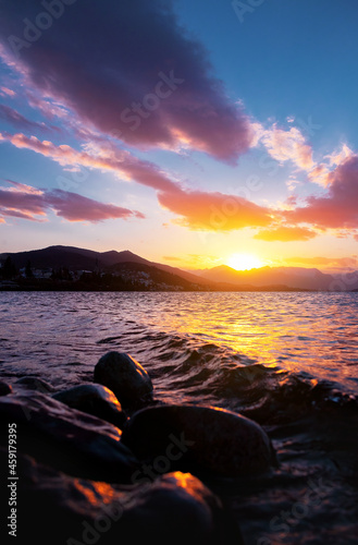 Canvas Print sunset in Bariloche lake shore with stones and calm water, mountains on the hori