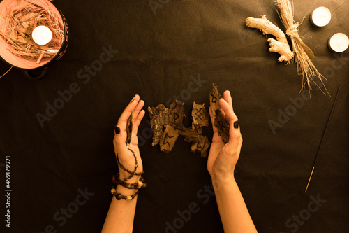 oráculo o lectura de runas de madera con manos de mujer sobre fondo negro   photo