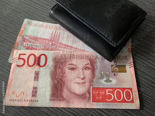 Sweden krone bills with black leather wallet isolated on dark wood background. Swedish krona money - 500 fem hundra kronor. 