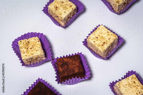 Various chocolate pralines candies in purple molds highlighted on a white background. Top view. The concept of goodies, delicious photography