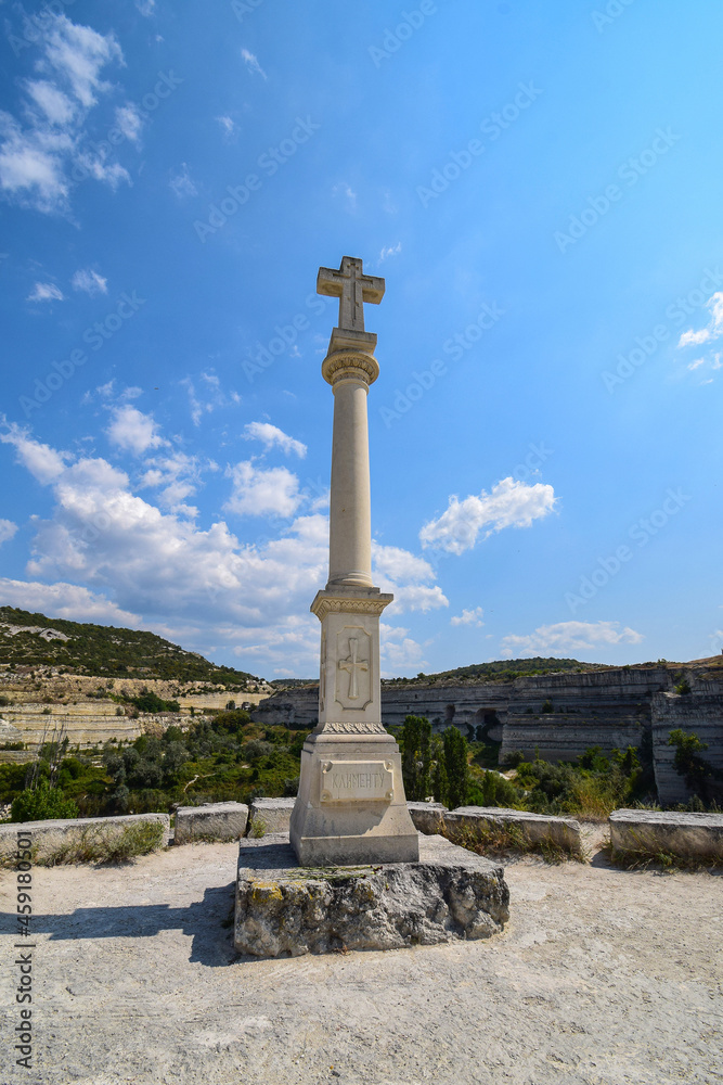 An obelisk with a cross standing at the top of a stone quarry