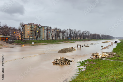 Muddy Nisava river is out of it's riverbank because of heavy rain and melted snow due to sudden weather change. Flood covered children playground and walking zone by the river photo