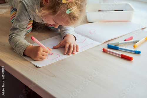 3 years girl draws a picture. Child at home, kindergarden and preschool closed during Covid-19 photo