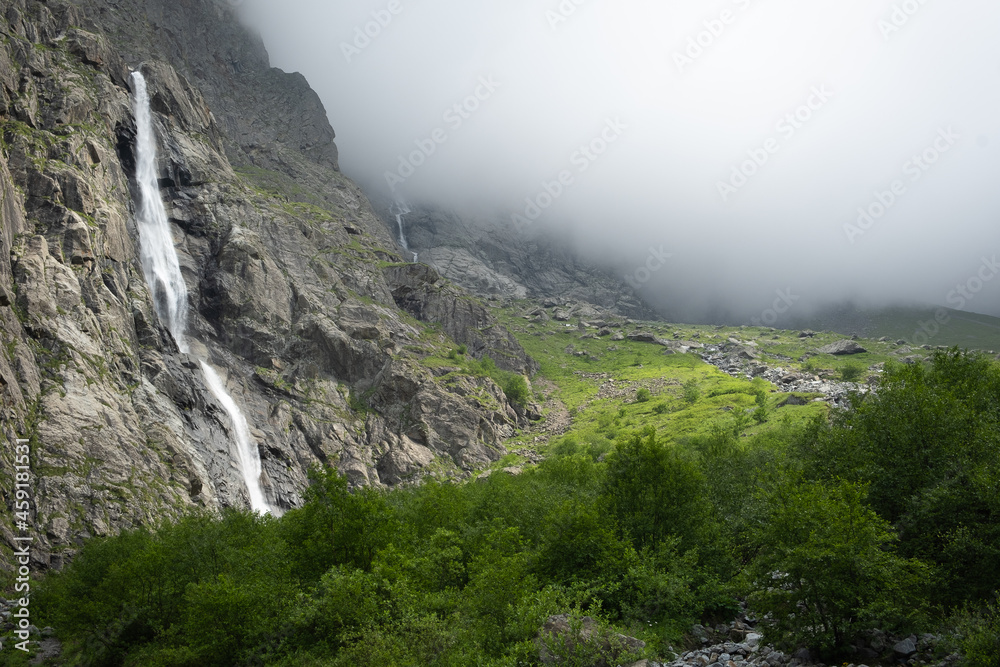 Majestic view of Midagrabin waterfall in sunlight in cloudy summer weather. Caucasus mountains. Russia. North Ossetia Alania