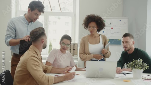 Group of confident young people discussing business while having meeting 